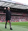 Erik ten Hag vinker til fans med Stretford End i bakgrunnen.