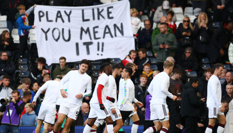 Bortefansen holder opp et banner hvor det står 'Play like you mean it!!' før kampstart mot Fulham.
