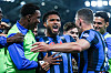 Flere Atalanta-spillere omfavner en spiller som jubler med åpen munn på banen under flomlys.