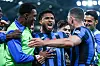 Flere Atalanta-spillere omfavner en spiller som jubler med åpen munn på banen under flomlys.