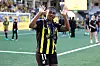 Fotballspiller i gulsvart Häcken-drakt vinker mot tribunen på en fotballbane.