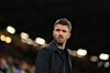 Michael Carrick i mørk jakke ser utover banen foran en belyst tribune.