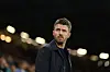 Michael Carrick i mørk jakke ser utover banen foran en belyst tribune.
