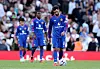 Manchester United-spillere i blå drakter står på banen, mens en spiller ser ned på ballen foran seg.