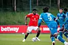 Carlos Baleba i rød Manchester United-drakt kjemper om ballen mot Lausanne-Sport-spillere i blå drakter.