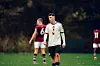 Kai Rooney i hvit Manchester United-drakt på en fotballbane, med spillere i bakgrunnen.