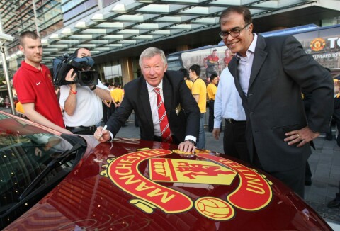 PÅ VEI UT: Sir Alex Ferguson signerer et bilpanser da United inngikk samarbeidet med Chevrolet i 2012. Nå er den amerikanske bilgiganten på vei ut av United.